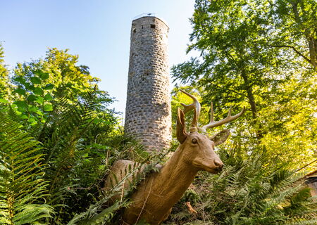 Wallenburger Turm mit einer Reh-Holzskulptur im Vordergrund